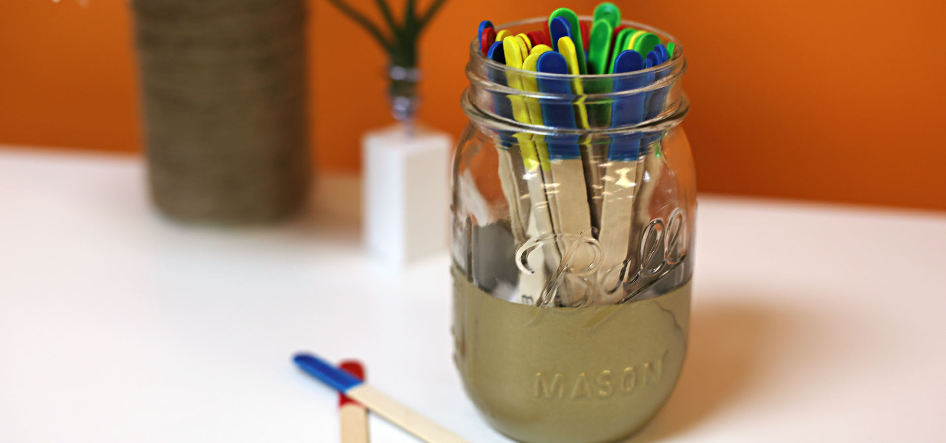 Glass jar with colored ice pop sticks