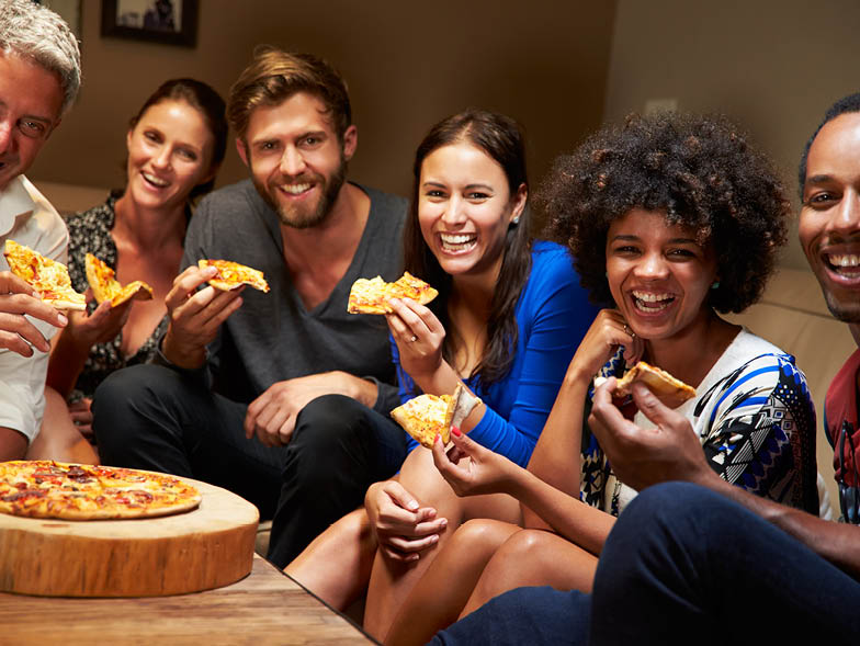 group of people laughing, eating pizza