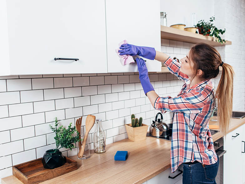 Woman wiping down kitchen cabinet