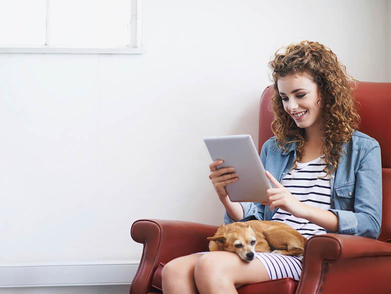 woman looking at ipad with dog on lap