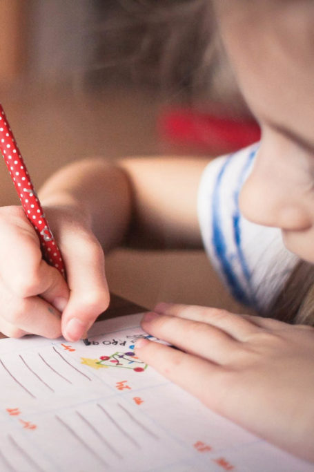 Young child drawing on paper with colored pencils