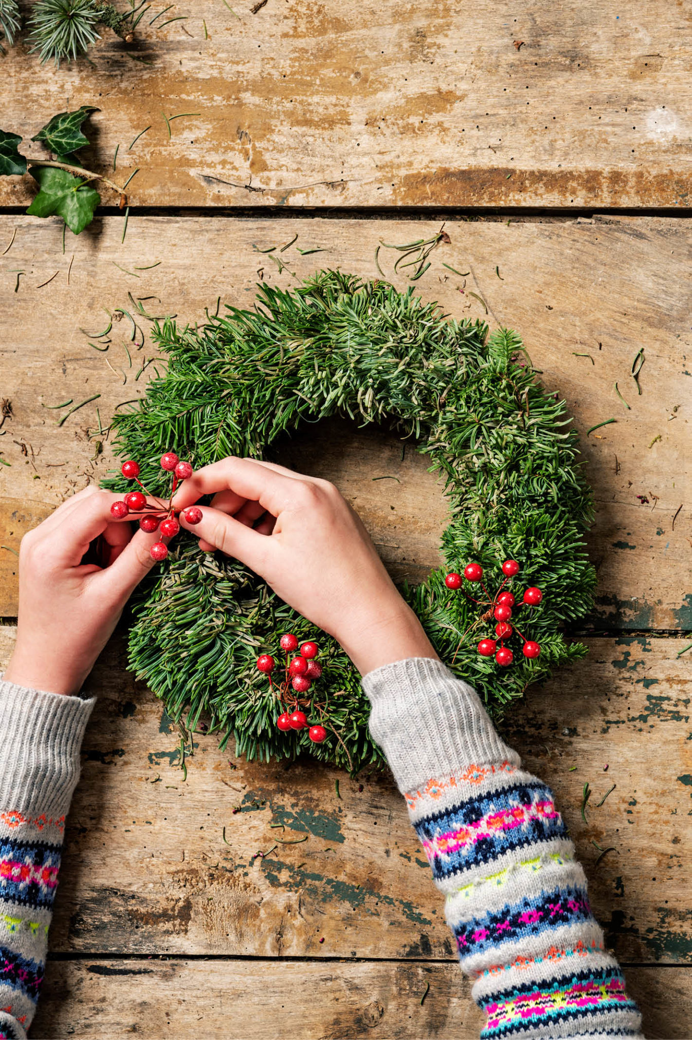adding holly to a green wreath
