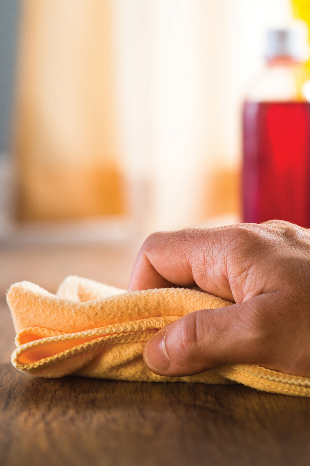Male hand wiping wooden surface with cleaning cloth