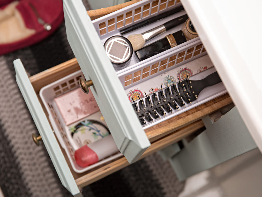Open drawers in bathroom sink cabinet showing use of trays to organize items