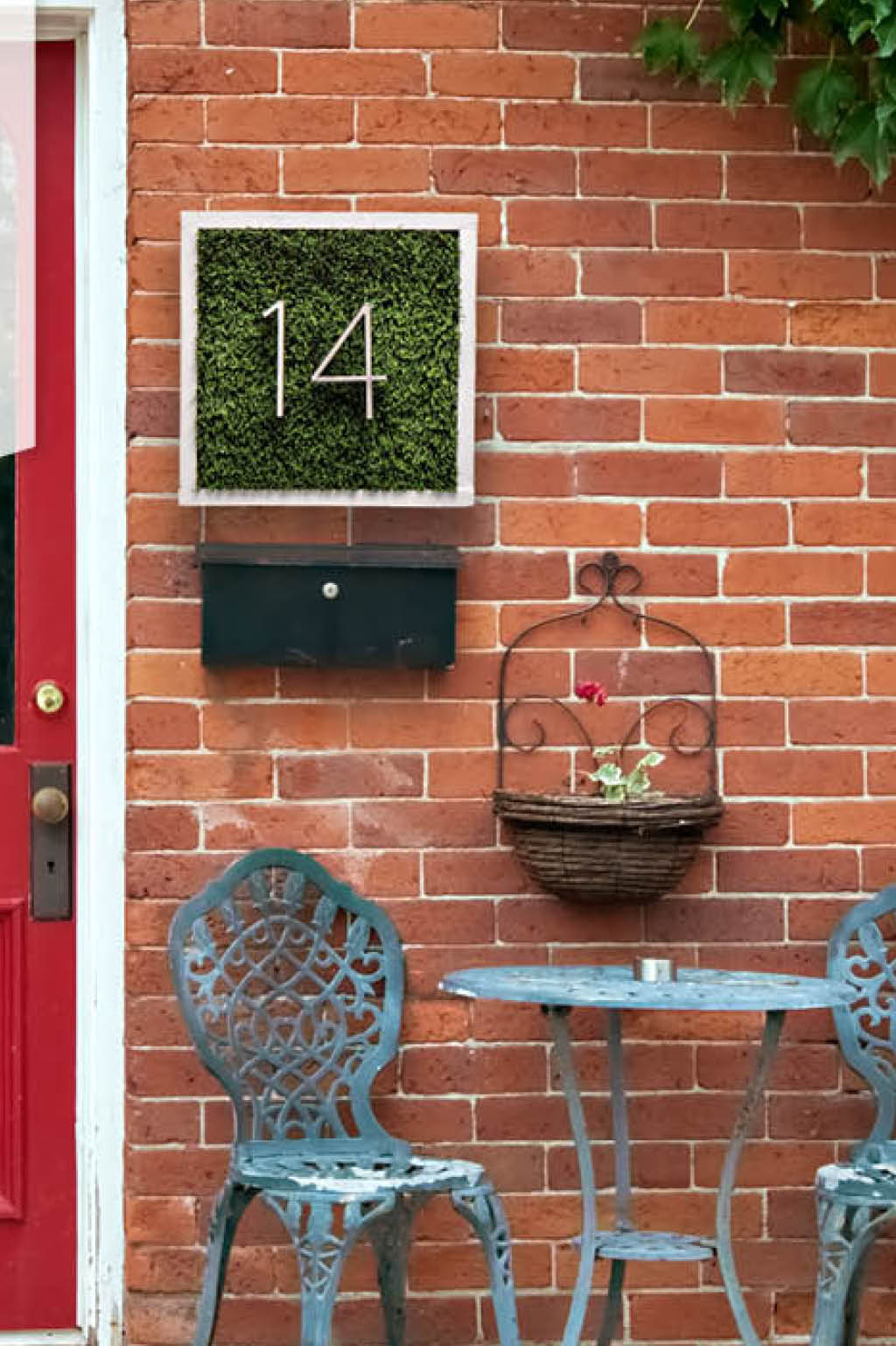 Front porch with red door and grassy house number