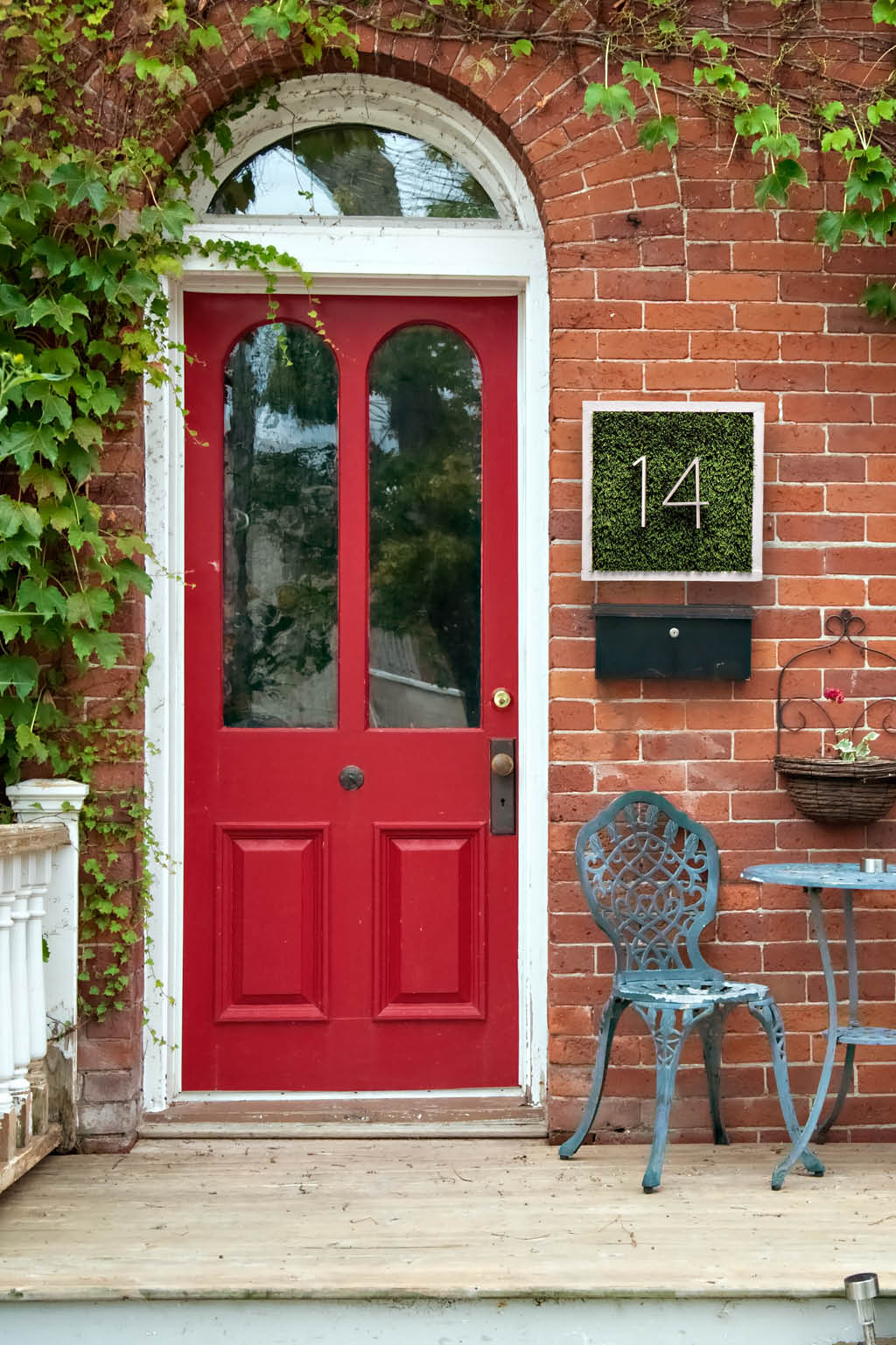 Front porch with red door and faux grass house numbers