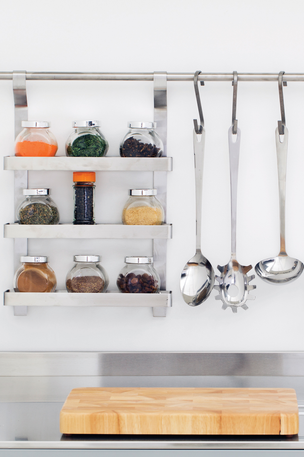 Kitchen utensils and spice rack hanging above sink
