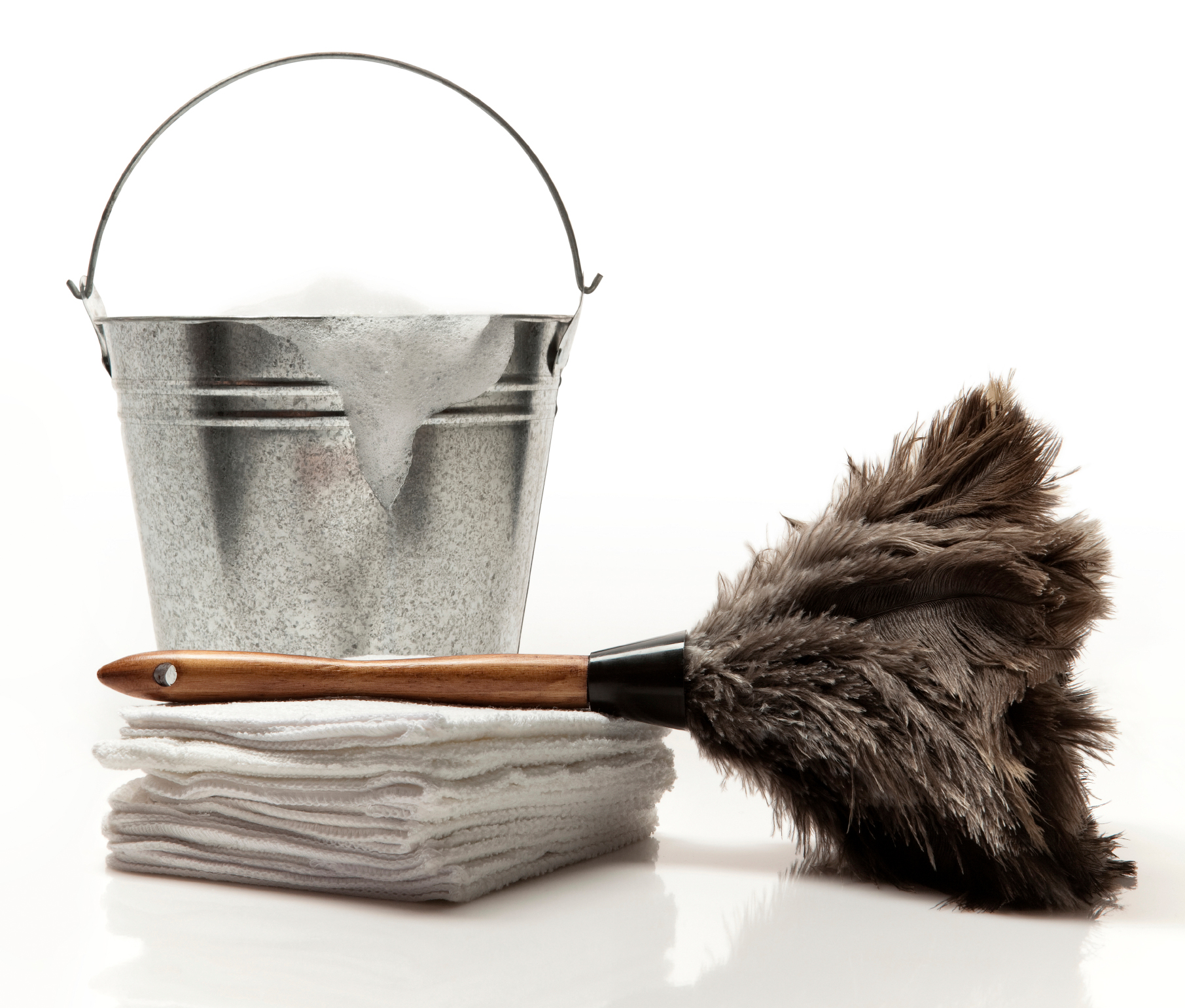 Metal pail bucket with soapy suds dripping out next to pile of cleaning towels and a feather duster