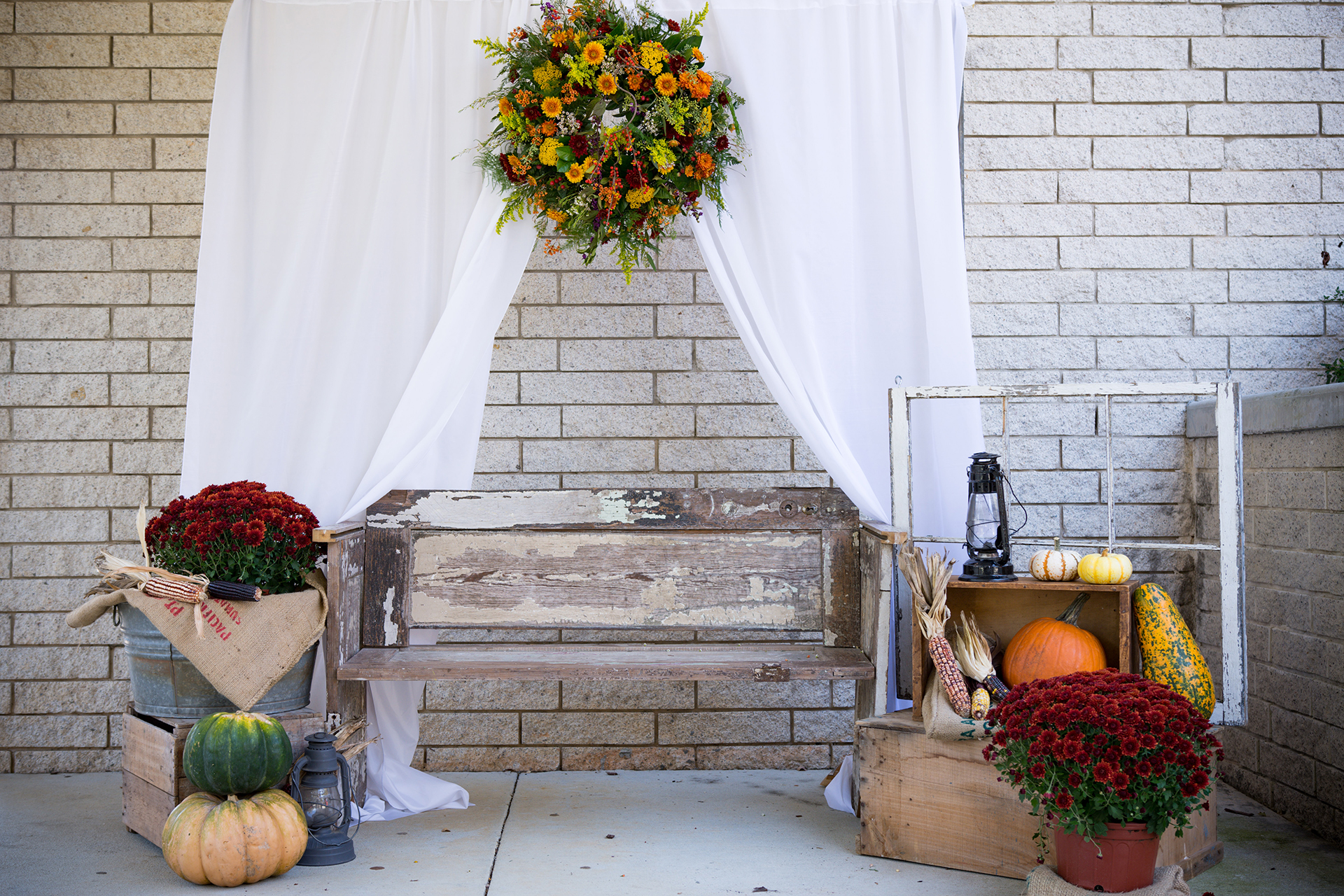 Front porch decorated with rustic items and burgundy flowers