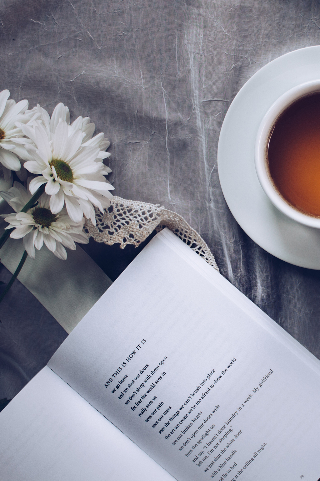 Open poetry book with cup of tea and white flowers