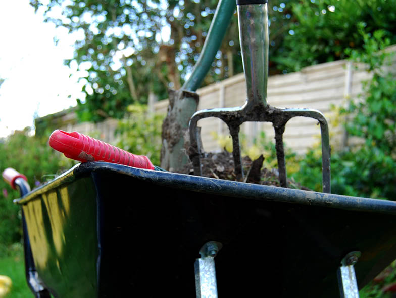 tools in a wheelbarrow of compost