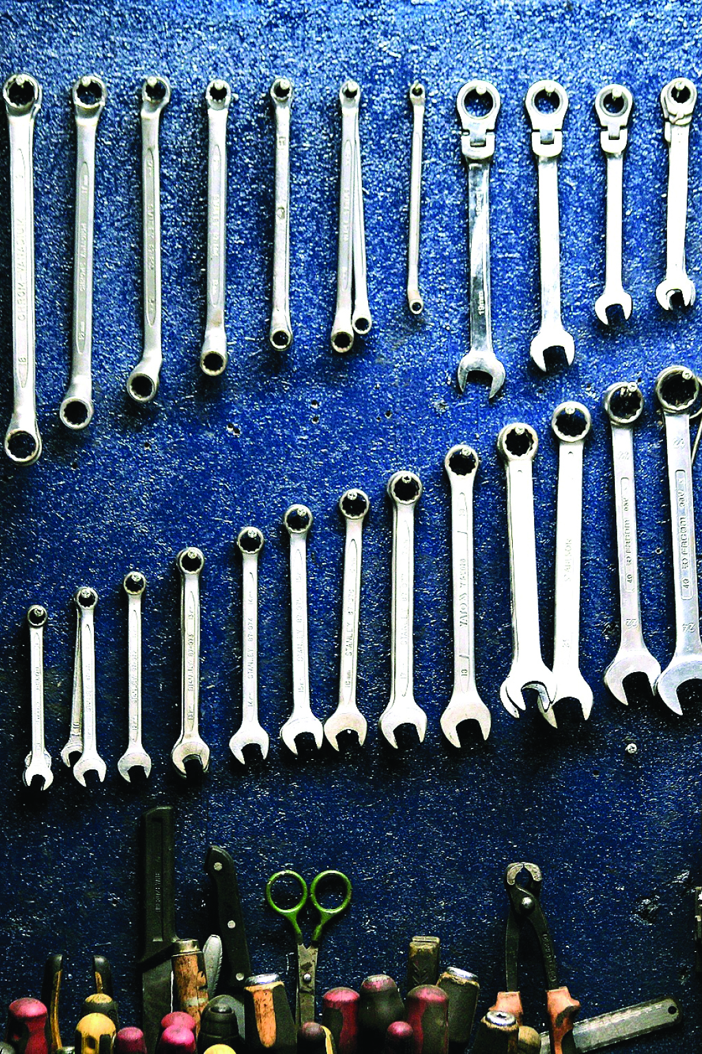 various wrenches organized along a blue wall