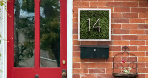 A front porch with a red door and homemade grassy house number