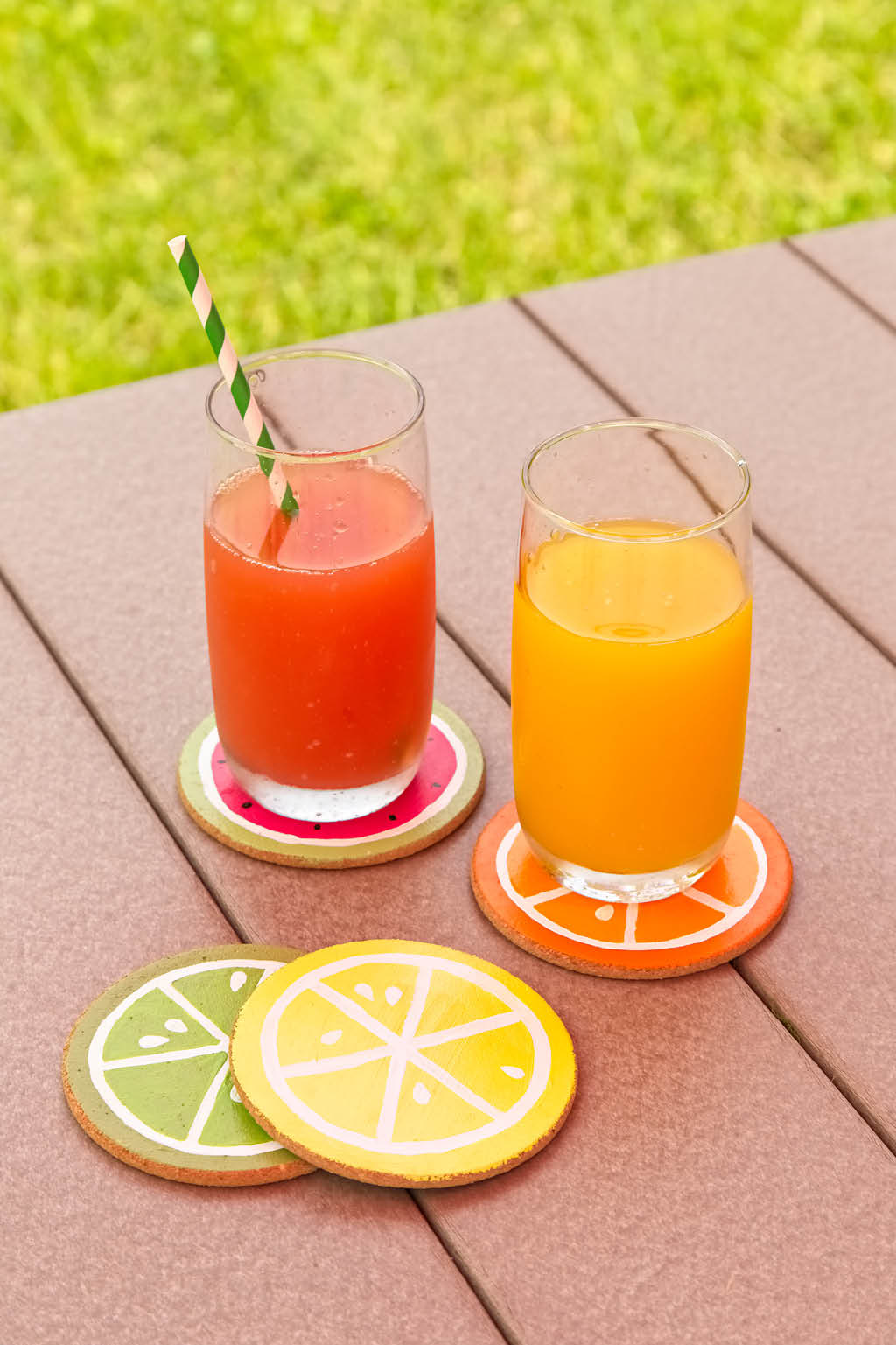 Glasses of juice on fruit-painted coasters