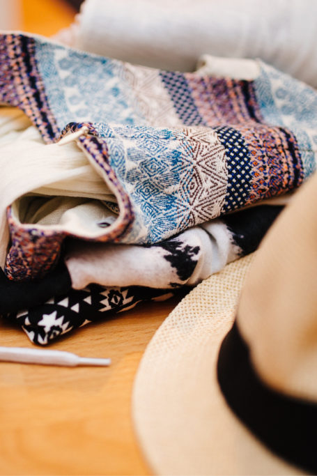 Folded pile of clothes with shoes and hat