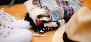 Folded pile of clothes with shoes and hat