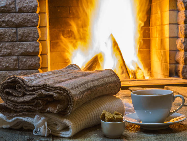 fireplace with folded blankets and a cup