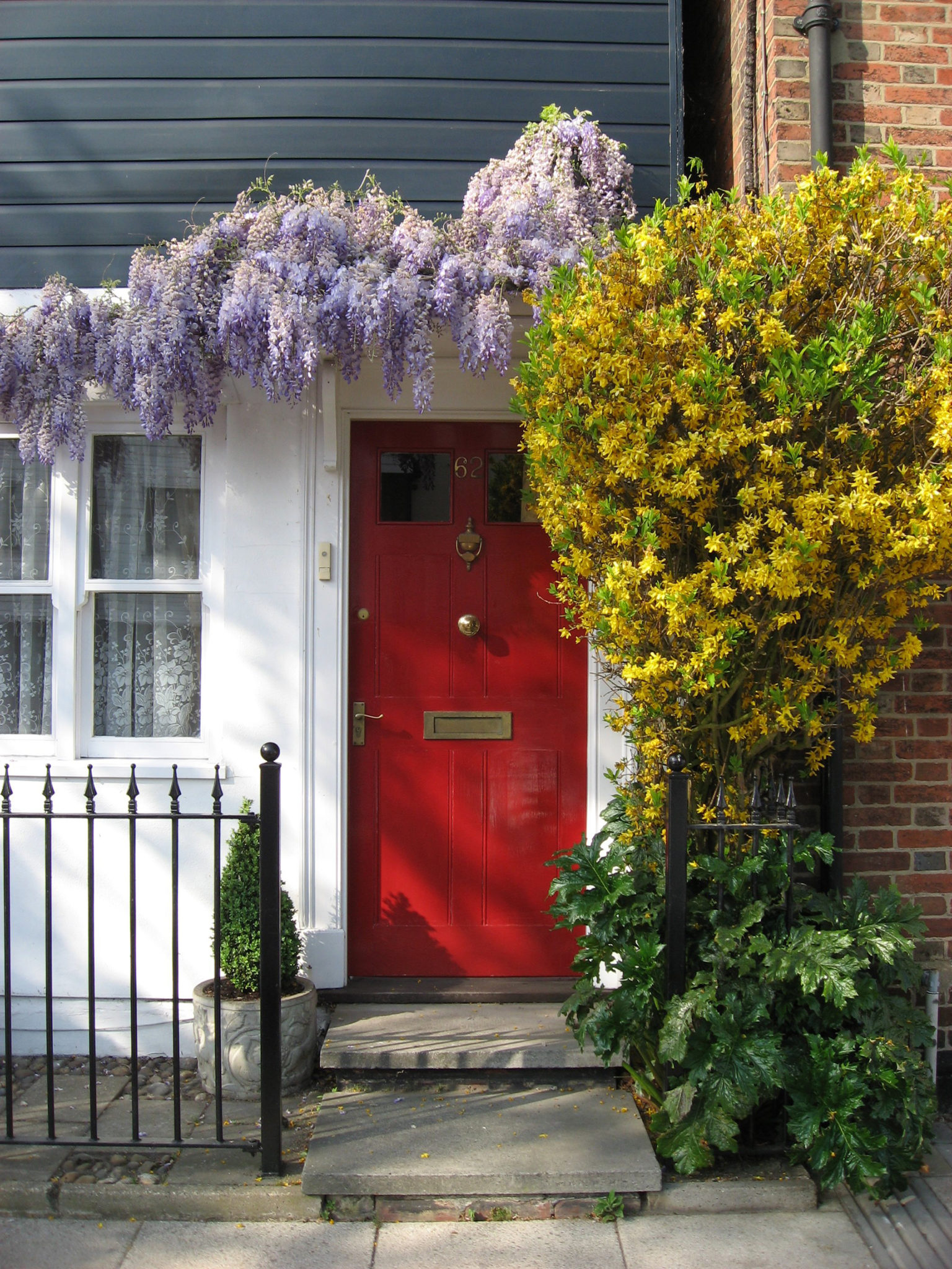 Front door painted red with flowers surrounding door