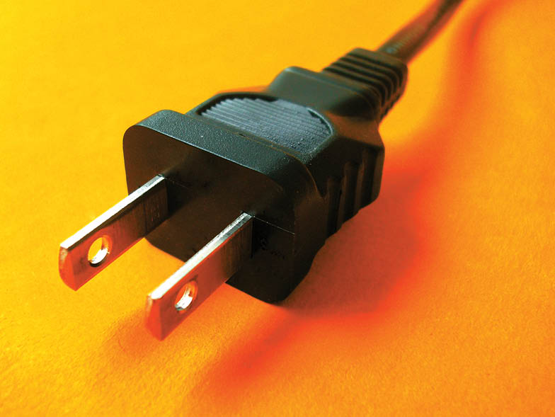 Close-up view of electrical plug against an orange background