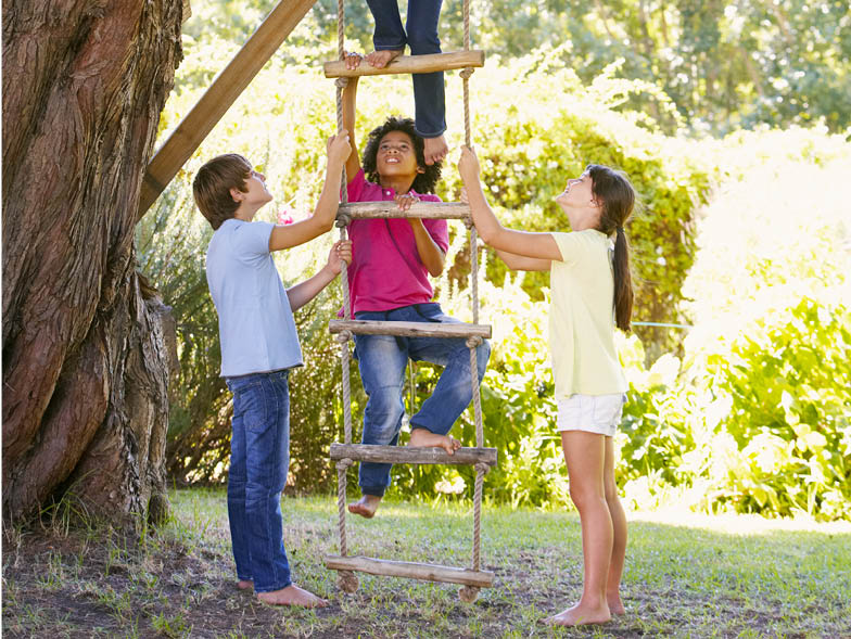 Children playing and climbing treehouse ladder