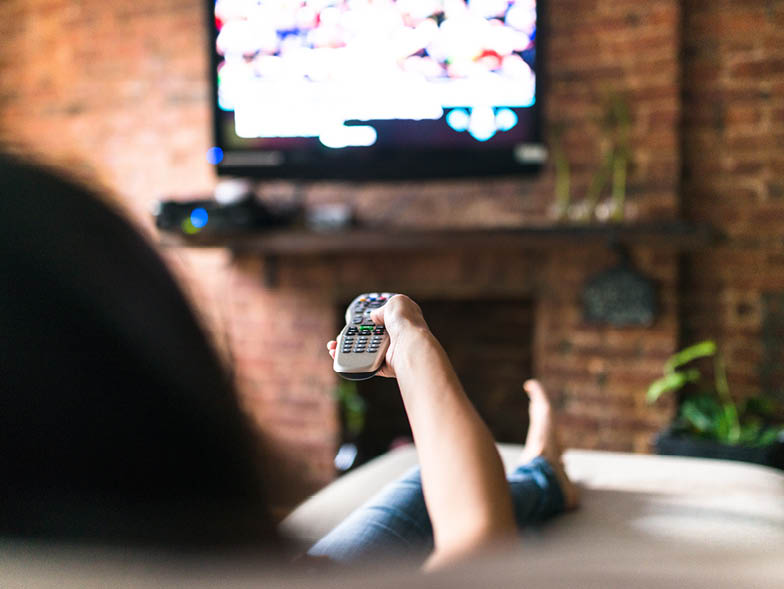 Female pointing a remote towards a TV
