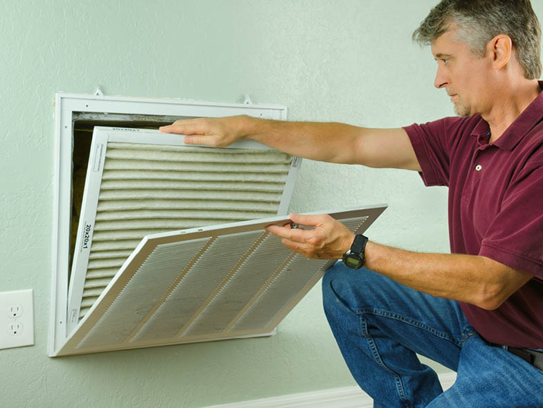 Man changing out air filter in vent