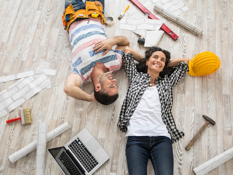 couple laying on ground with tools surrounding them taking a break from home improvement