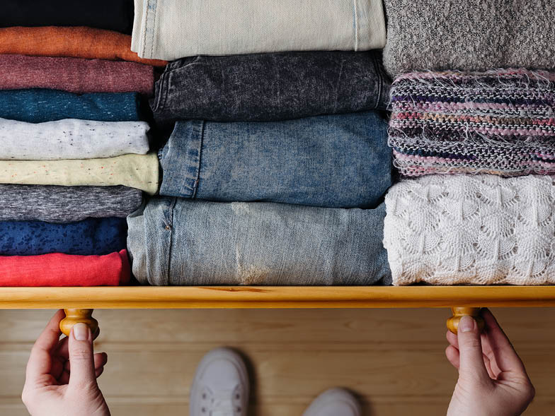hands pulling dresser drawer open with organized clothing folded inside