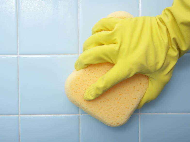 Gloved hand scrubbing tiles