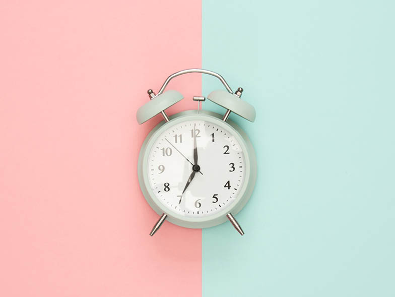 Teal alarm clock on pink and teal background