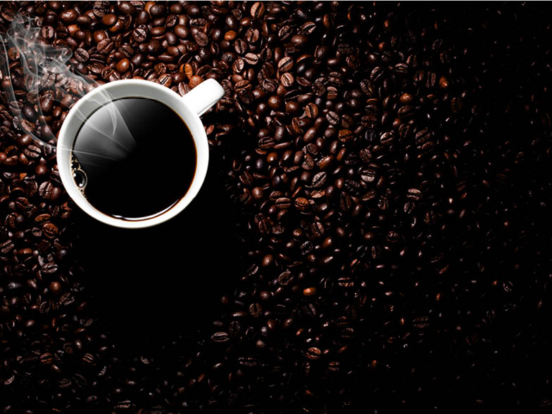 Cup of steaming coffee on top of background of coffee beans