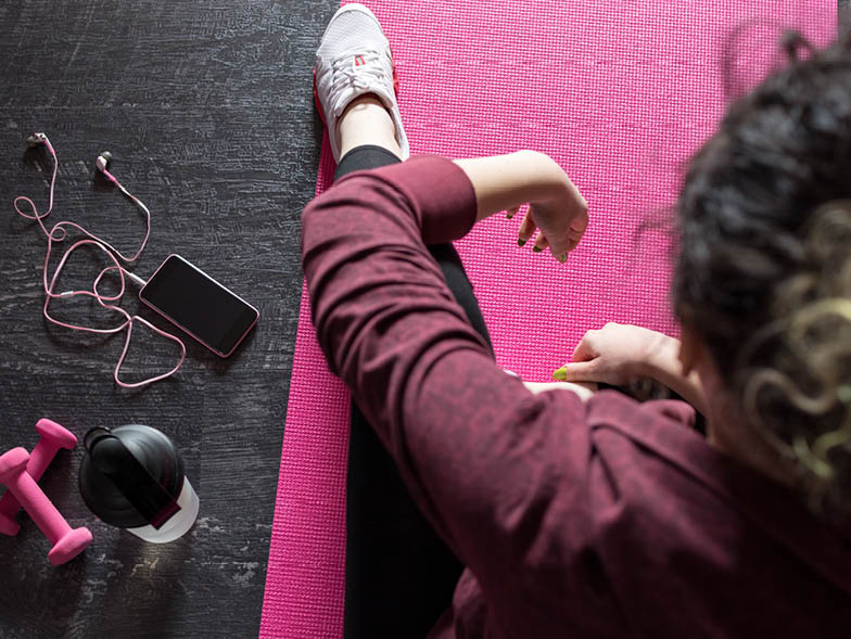 woman sitting on pink mat with exercise equipment