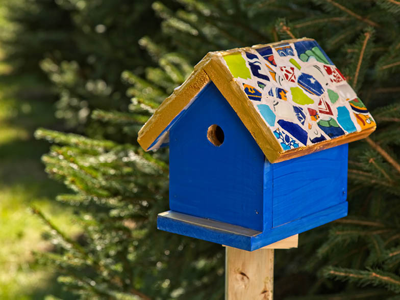 Homemade birdhouse with roof made of broken tiles