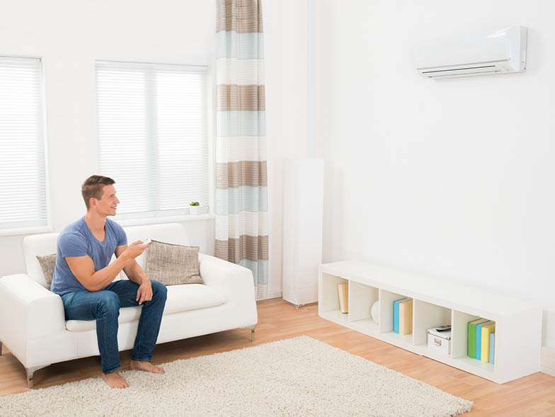 Man pointing remote at air conditioning unit
