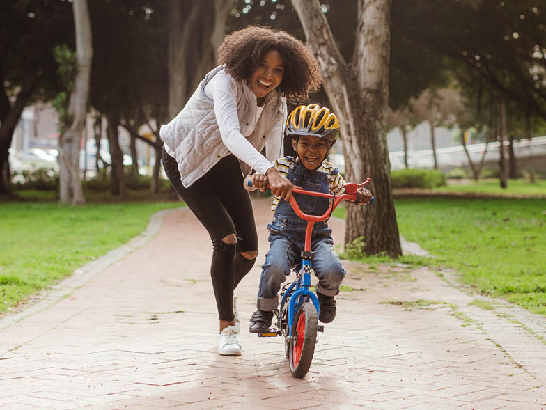 Woman helping son learn how to ride bike
