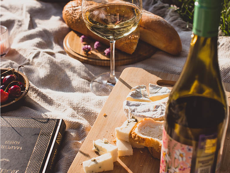 Wine, cheese, and bread on a picnic blanket