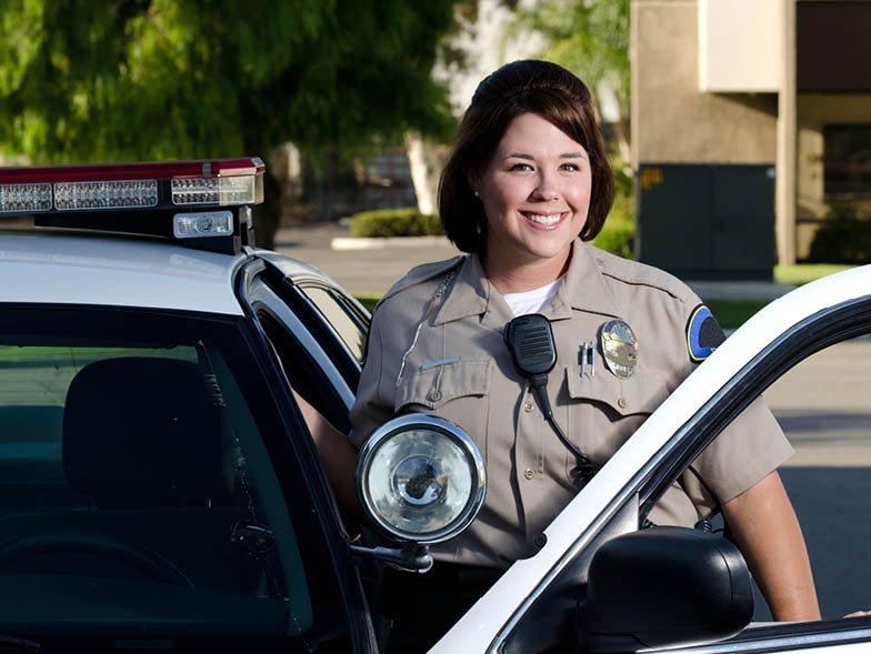 Police woman smiling and standing beside car