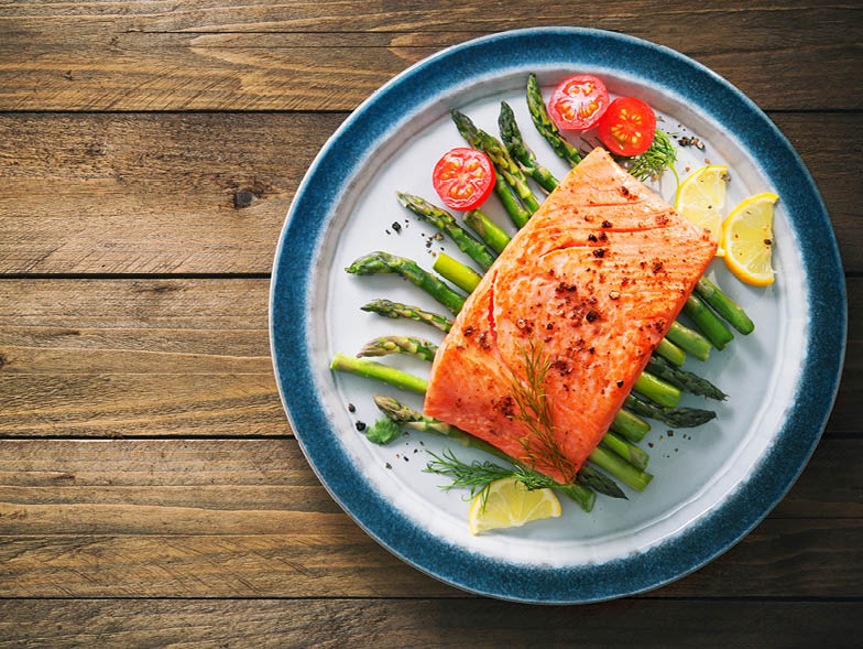 Salmon on plate with asparagus, tomatoes, and lemon