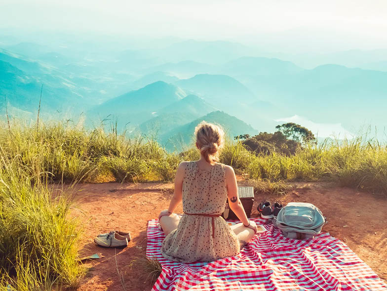 Woman sitting on picnic blanket overlooking mountains