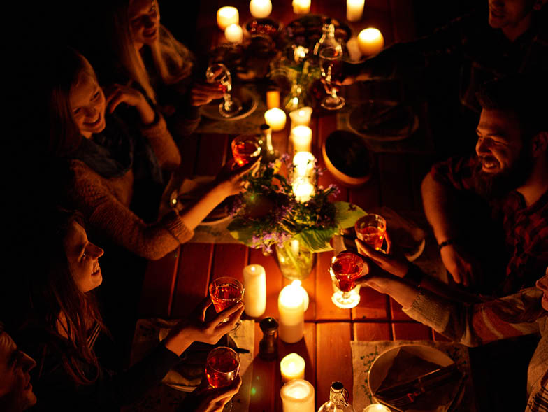 Friends gathered around table with many candles