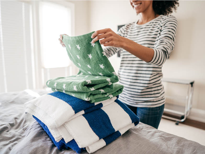 Smiling woman folding towels on bed