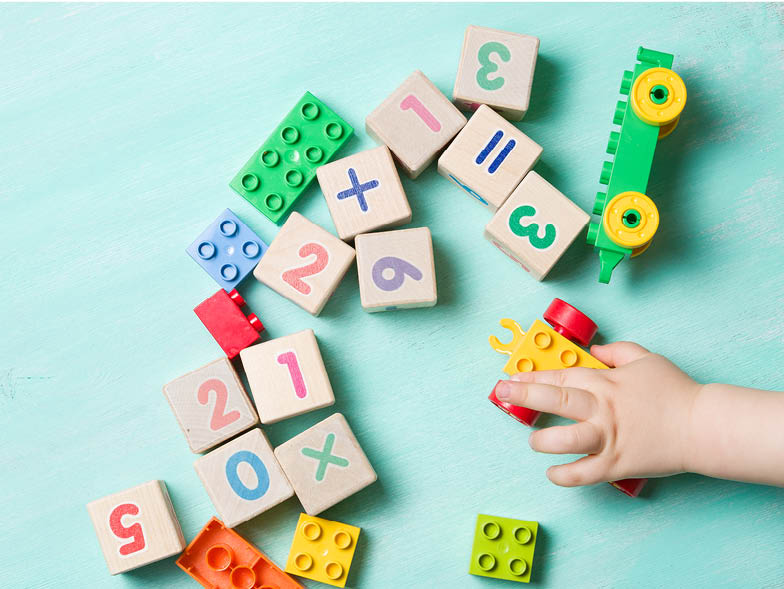Children's toys on teal surface with child's hand reaching in