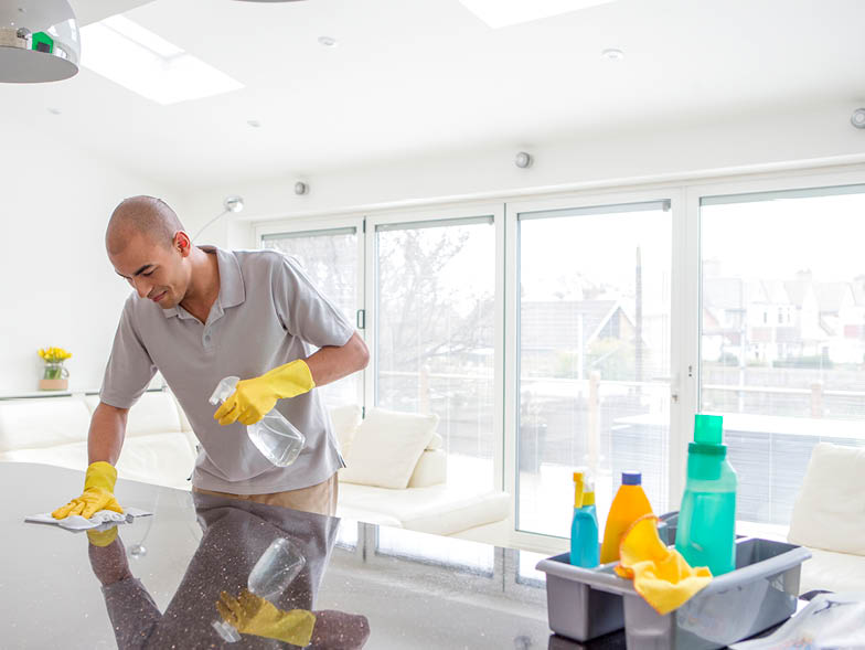 Man scrubbing kitchen counters wearing yellow gloves