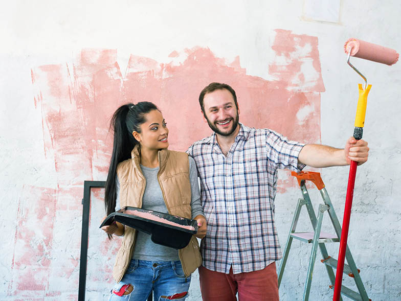Couple painting white wall pink