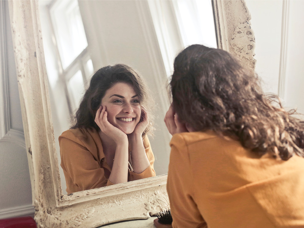 Woman looking at reflection in white framed mirror