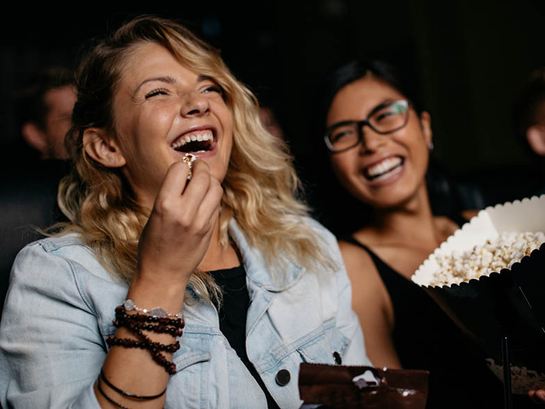 Women laughing at movie in theater