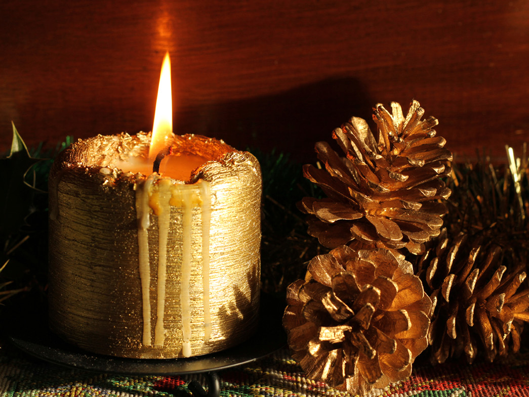 Gold candle next to pinecones