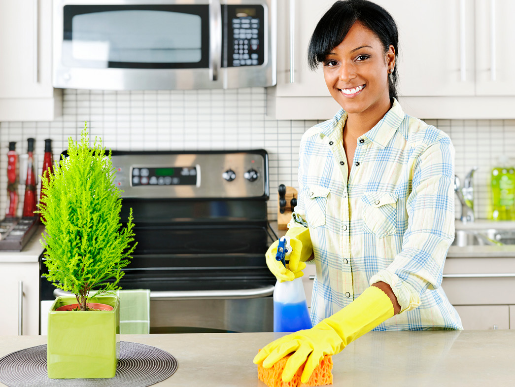 Woman smiling and cleaning kitchen counter