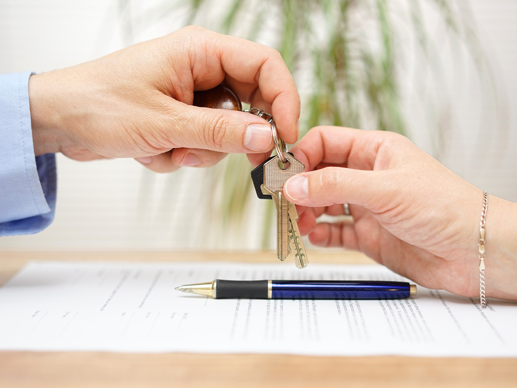 Hands passing keys over document and pen