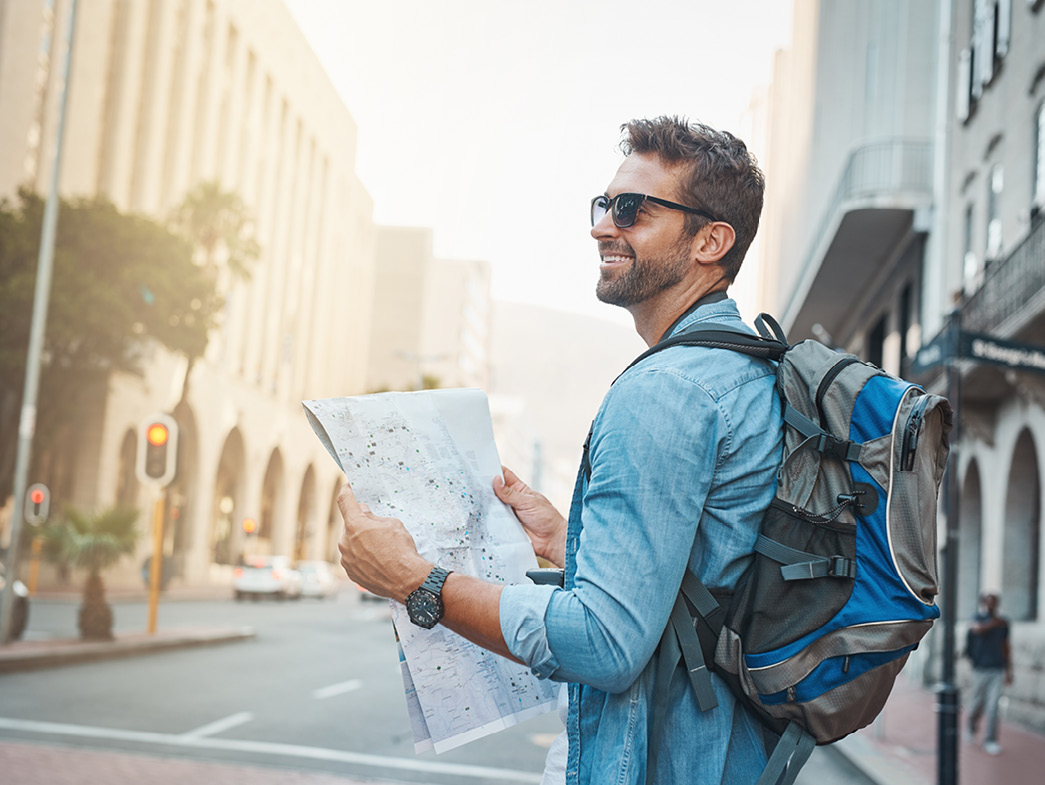 Man with backpack holding up map and smiling